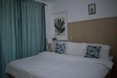 a bedroom with a large white bed with green curtains at Villa Brise de Mer in Las Terrenas