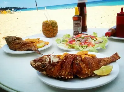 a table with two plates of food on the beach at Casa Linda - 10 mins from Beach & Lagoon with AC & Free Parking in Payita