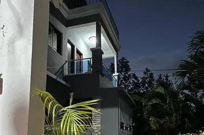 a house with a balcony with a light on it at Casa Linda - 10 mins from Beach & Lagoon with AC & Free Parking in Payita