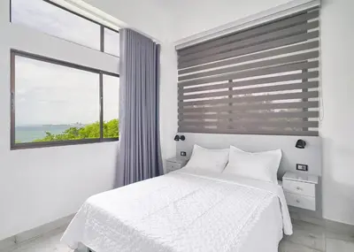 a bedroom with a white bed and a large window at spectacular sea view in Santo Domingo