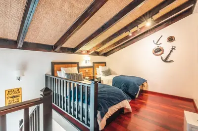 a attic bedroom with two beds and a staircase at Gorgeous PH at Puerto Bahia in Santa Bárbara de Samaná
