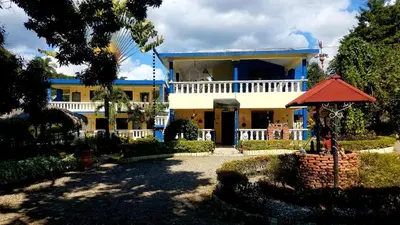 a large yellow house with a blue roof at Sana El Jardin Secreto in Santiago de los Caballeros