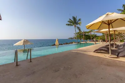 a swimming pool with chairs and umbrellas next to the ocean at 