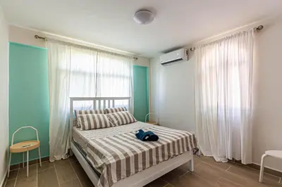 a bedroom with a bed with a striped blanket and two windows at Monte Vista Apartments in Sosúa