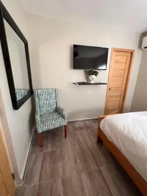 a bedroom with a bed and a chair and a television at Hostal 53 Boutique Santo Domingo in Santo Domingo