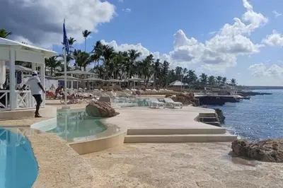 a person standing next to a swimming pool at a resort at El Rinconcito Caribeño in La Laguna