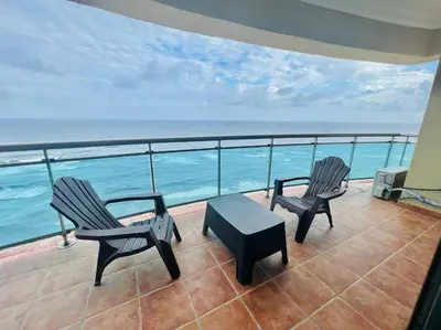 two chairs and a table on a balcony with the ocean at Beach Front Penthouse in Exclusive Tower in Santo Domingo