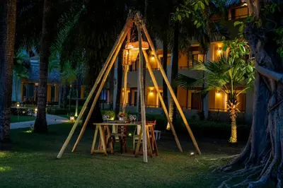 a table and a swing in a yard at night at Iberostar Waves Costa Dorada - All Inclusive in San Felipe de Puerto Plata