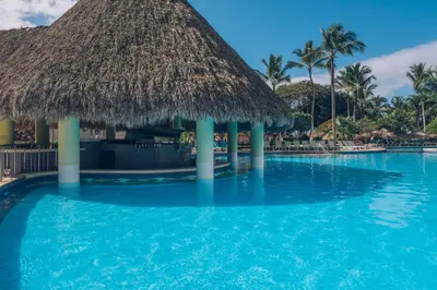 a swimming pool at a resort with a thatched roof at Iberostar Selection Hacienda Dominicus - All Inclusive in Bayahibe