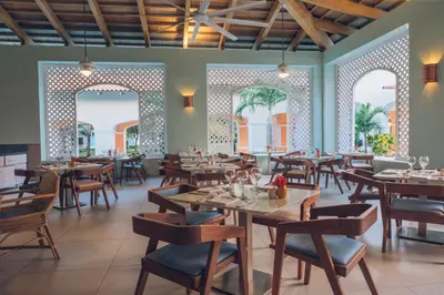 a restaurant with wooden tables and chairs and arches at Iberostar Selection Hacienda Dominicus - All Inclusive in Bayahibe