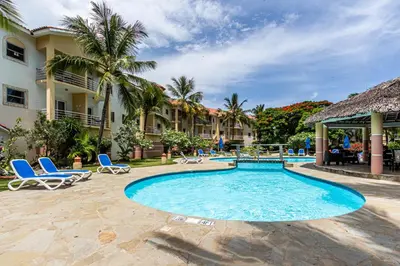 a pool at a resort with blue chairs and palm trees at Ocean Dream Studios, kiters paradise! in Cabarete