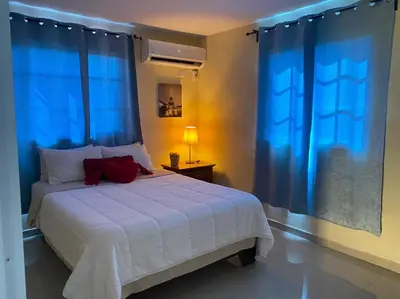 a bedroom with a white bed with blue curtains and a bed sidx sidx sidx sidx at Tiny Apartment By Merengue House ,8 minutos airport in Santo Domingo