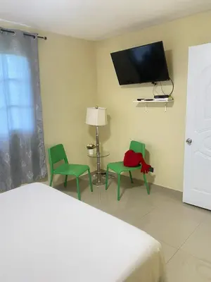 a bedroom with two green chairs and a flat screen tv at Tiny Apartment By Merengue House ,8 minutos airport in Santo Domingo