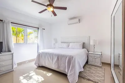 a white bedroom with a bed and a ceiling fan at Paradise Condos, Cabarete! in Cabarete