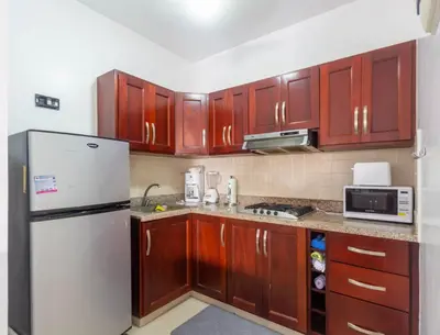 a kitchen with wooden cabinets and a white refrigerator at Paradise Condos, Cabarete! in Cabarete