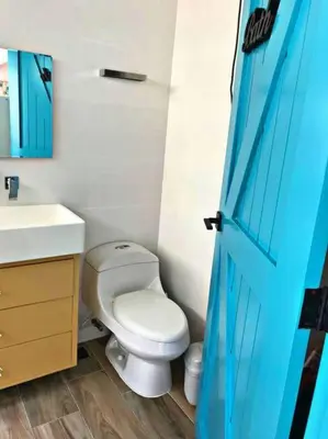 a bathroom with a toilet and a sink and a blue door at Amazing apartment, B-Juan Dolio, El Bonio II in Juan Dolio