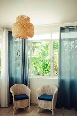 two chairs in front of a window with blue curtains at Sueño Caribeño in La Laguna
