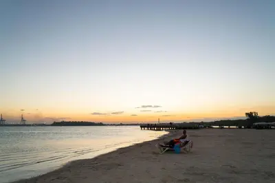 a man sitting on a chair on the beach at sunset at Villa Gumio Studio Apt - 7 minutes walk to Boca Chica Beach apts in Boca Chica