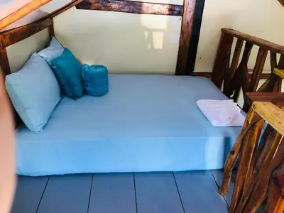 a bed in a room with blue sheets and blue pillows at Baby Rustic in Punta Rucia