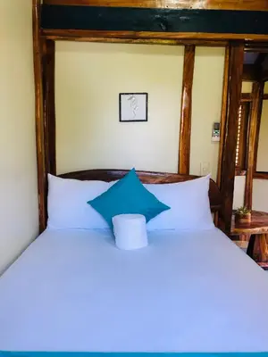 a bedroom with a white bed with a blue pillow at Baby Rustic in Punta Rucia
