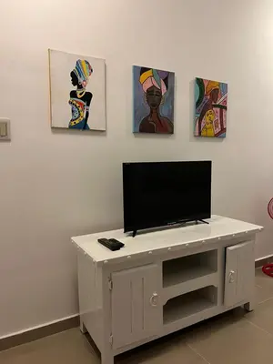 a tv on a white table in a room with paintings at Apartamento a 5 minutos Zona Colonial in Santo Domingo
