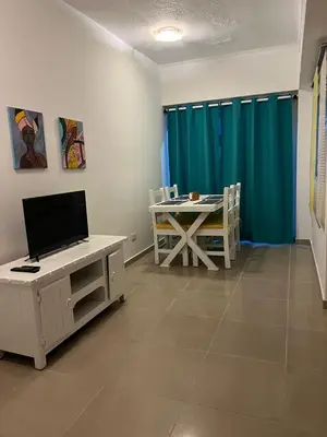a room with a table with a television and a table with a blue curtain at Apartamento a 5 minutos Zona Colonial in Santo Domingo