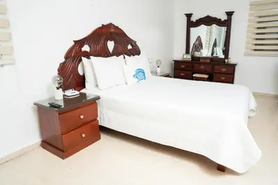 a bedroom with a large white bed and a wooden dresser at Apartamento Los Anturios en Puerto Plata Bayardo in San Felipe de Puerto Plata