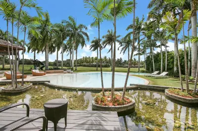 a swimming pool with palm trees in a park at Luxurious 8-BR Villa with Ocean View, Jacuzzi, Home Cinema and Resort Access in Casa de Campo in La Romana