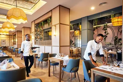 two chefs working in a restaurant with tables at Riu Palace Macao - Adults Only - All Inclusive in Punta Cana