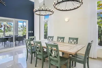 a dining room with a wooden table and green chairs at Stunning 3-Bedroom Villa with Pool, Jacuzzi and Maid near Bavaro Beach in Punta Cana