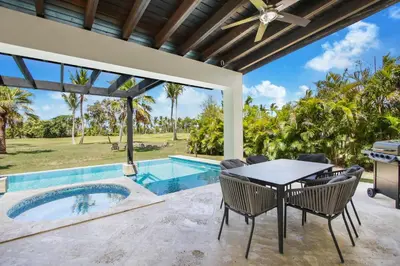 an outdoor patio with a table and chairs and a swimming pool at Stunning 3-Bedroom Villa with Pool, Jacuzzi and Maid near Bavaro Beach in Punta Cana
