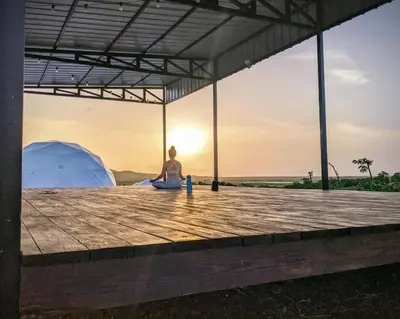 a woman sitting on a dock with a tent in the background at Domescape Glamping in El Cedro