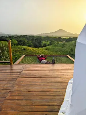 a person sitting on a wooden deck looking at the mountains at Domescape Glamping in El Cedro