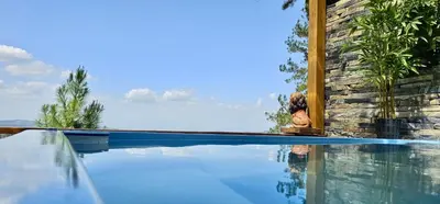 a person sitting next to a swimming pool at Villa Leon in Jarabacoa