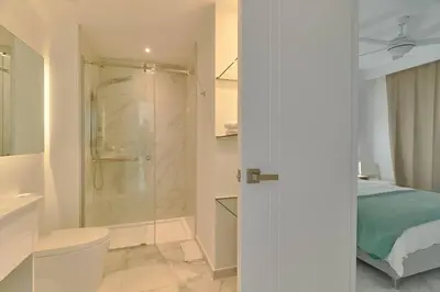 a bathroom with a shower and a toilet and a bed at Luxury Apartment at Cana Rock Star Punta Cana DR in Punta Cana