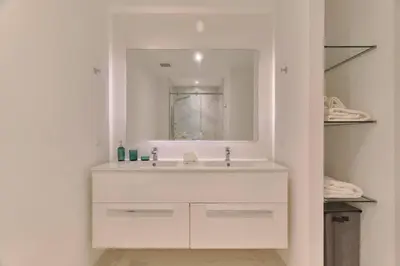 a white bathroom with a sink and a mirror at Luxury Apartment at Cana Rock Star Punta Cana DR in Punta Cana