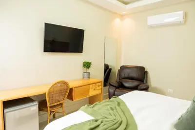 a bedroom with a bed and a desk with a television at Hotel Stay Here Suites in Santo Domingo