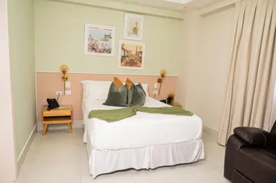 a bedroom with a large white bed with green pillows at Hotel Stay Here Suites in Santo Domingo