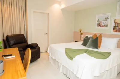 a bedroom with a bed and a leather chair at Hotel Stay Here Suites in Santo Domingo