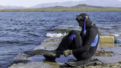 a man sitting on the edge of a body of water at Sava Salinas in Las Salinas