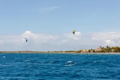 two kites flying in the sky over the ocean at Sava Salinas in Las Salinas