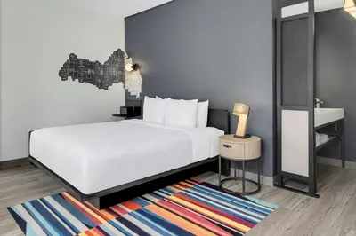 a bedroom with a white bed and a colorful rug at Aloft Santo Domingo Piantini in Santo Domingo