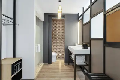 a bathroom with a white sink and a brick wall at Aloft Santo Domingo Piantini in Santo Domingo