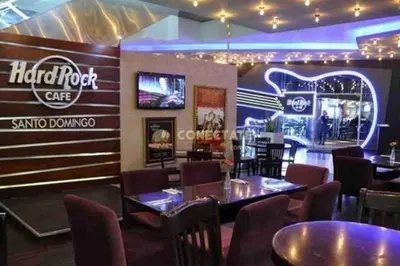 a restaurant with tables and chairs and a sign for a hip root cafe at VIP DELUXE SUITE AND TOWER E11 POOL_GYM_SAUNE_WIFE in Santo Domingo