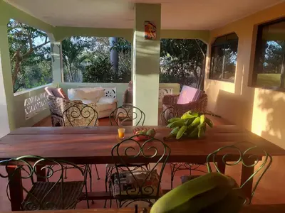 a wooden table and chairs on a screened in porch at La Hacienda Hostel-Rancho in Las Galeras