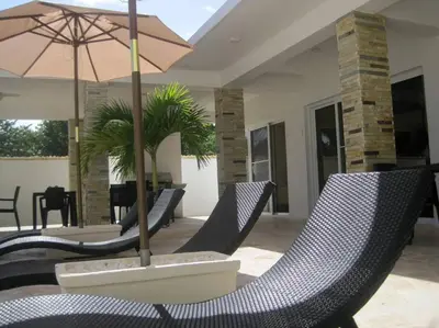 a patio with chairs and a table with an umbrella at Villa Palmas Doradas in Cabarete