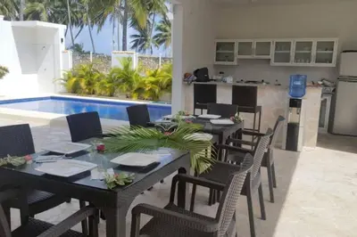 a dining room with a table and chairs and a pool at Villa Palmas Doradas in Cabarete