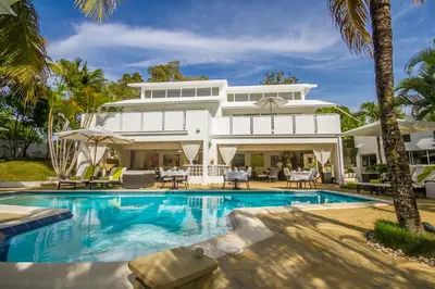 a large white house with a swimming pool and palm trees at Casa Veintiuno in Sosúa