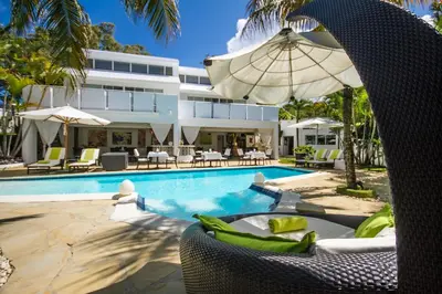 a resort with a swimming pool with chairs and an umbrella at Casa Veintiuno in Sosúa