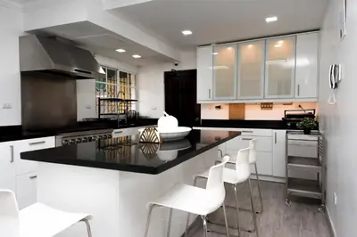 a kitchen with white cabinets and black counter tops at 8BR Penthouse Jacuzzi, Pool Table Terrace in Los Prados